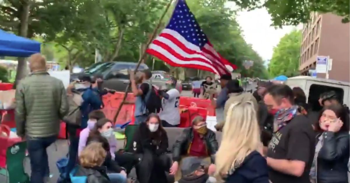Black Man Defies Hateful Protesters to Their Faces, Carries
American Flag Right Through ‘CHAZ’ 1