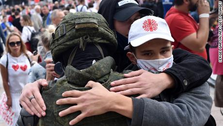Belarus riot police drop shields and are embraced by
anti-government protesters 1