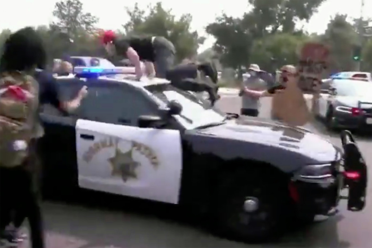 Anti-Trump protester jumps on police cruiser — is quickly
tossed off 1